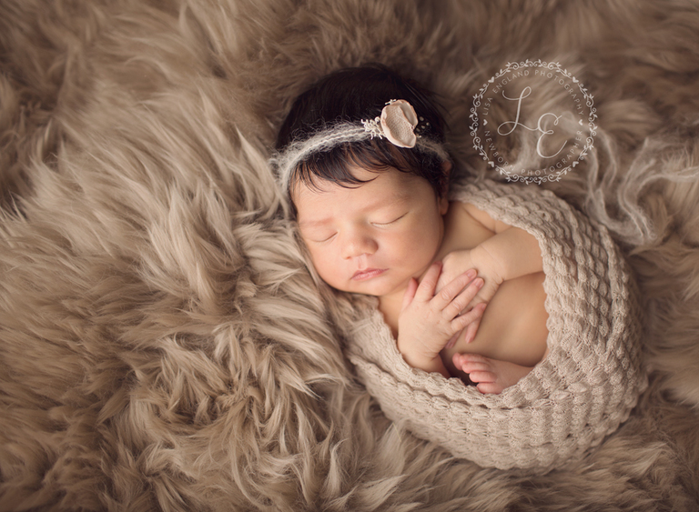 infant girl wrapped on tan sheepskin rug