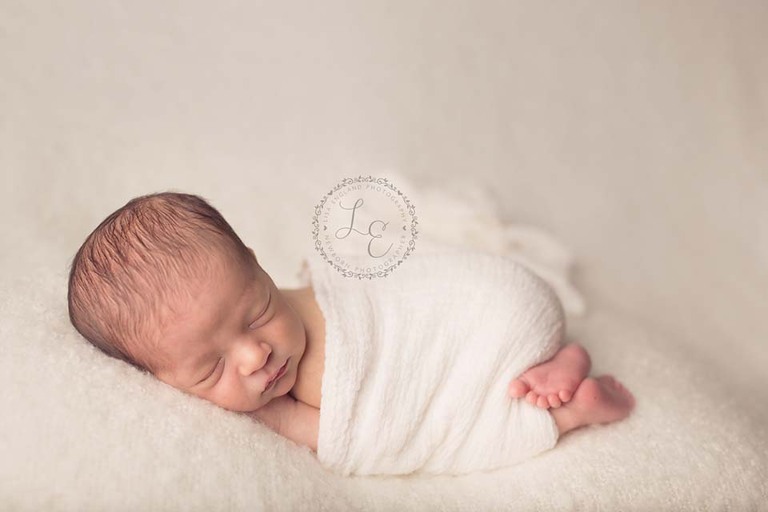 baby boy wrapped on cream blanket