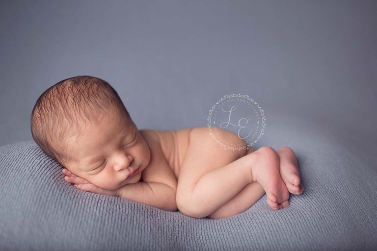 newborn laying on side on blue backdrop