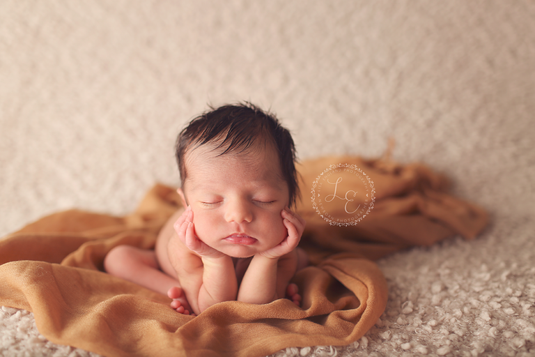 infant with chin in hands on brown scarf