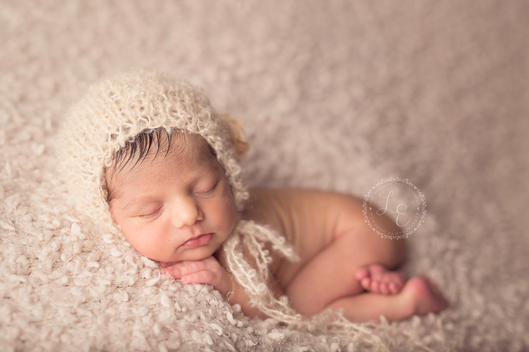 baby girl laying on tummy with cute cream hat