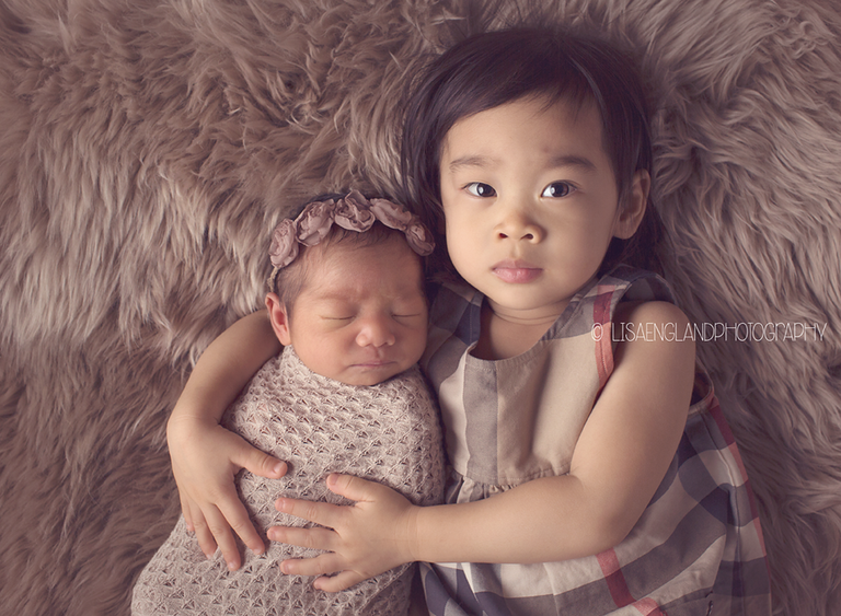 big sister holding her new baby sister
