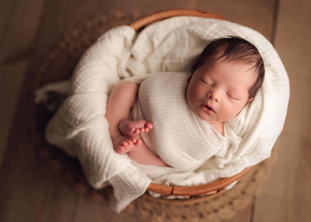 swaddled baby boy sleeping in a basket during his newborn session in san diego