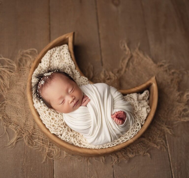 Tiny newborn girl wrapped in cream, sleeping in a moon shaped wooden bowl prop - Lisa England Photography, San Diego lifestyle newborn photography