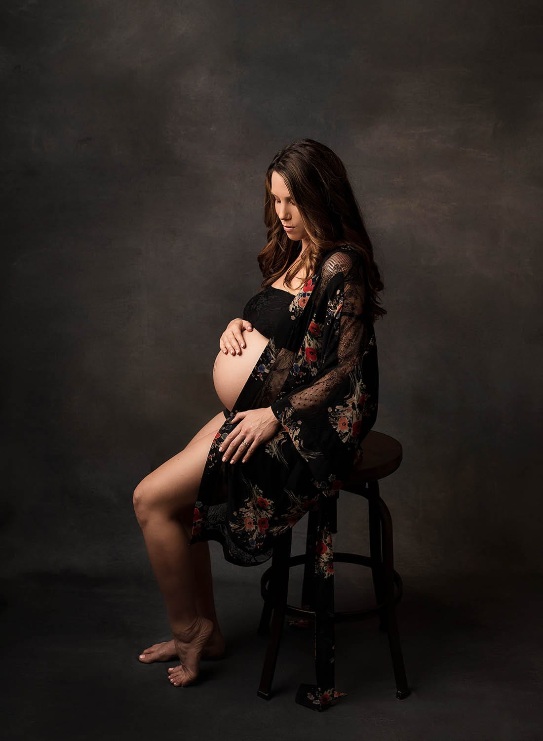 beautiful pregnant lady sitting on a barstool in a robe