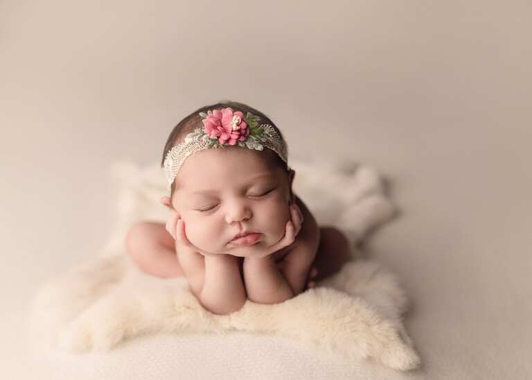 Newborn session in San Diego. Newborn baby girl sleeping on a cream fur in the froggy pose.