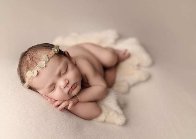 Newborn session in San Diego. Newborn baby girl sleeping posed on a cream fabric