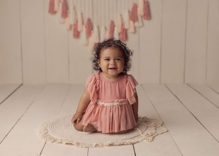Baby milestone session. One year old baby girl in a pretty pink dress.