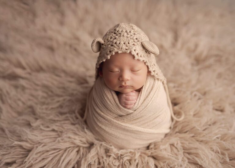 Baby girl sleeping wrapped in a all cream set up, wearing a crochet bear bonnet - Lisa England Photography, San Diego Baby Photography