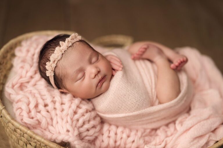 Sweet baby girl sleeping on a soft pink layer during her newborn session in San Diego