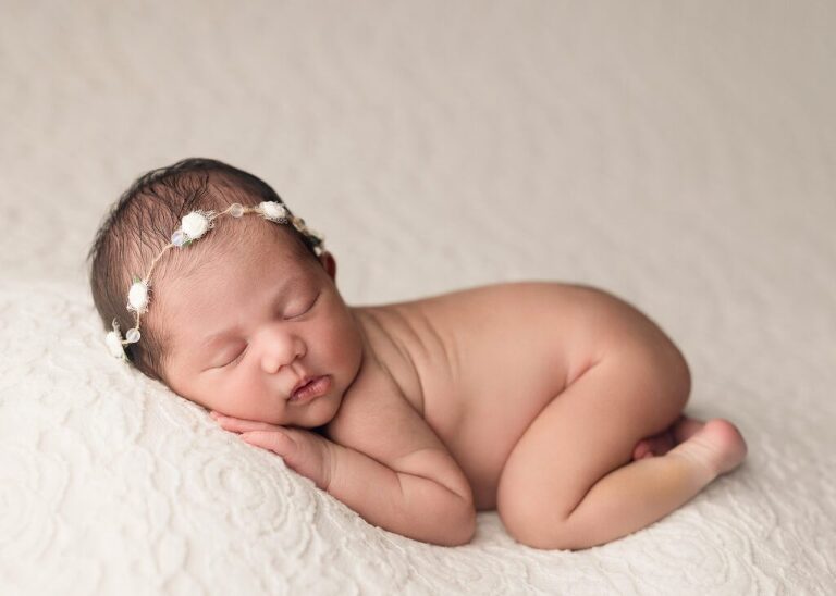 Precious girl gently posed on a soft fabric during her newborn session in San Diego