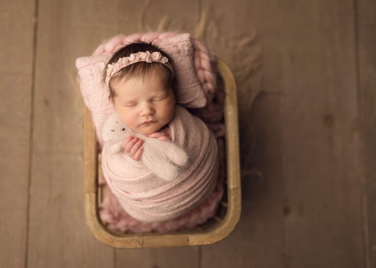 newborn girl wrapped in light pink holding a matching teddy bear, san diego newborn photography studio