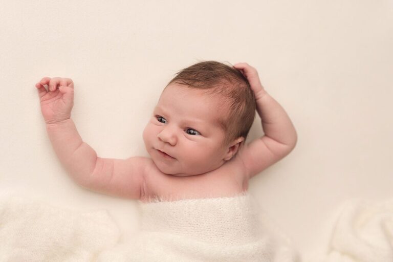 awake baby girl striking a natural pose during her baby-led newborn session in San Diego