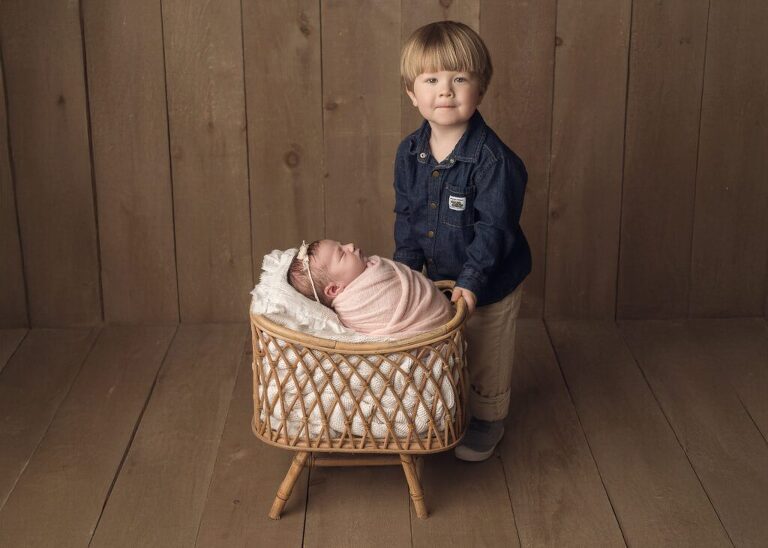 Big brother standing proudly next to his new baby sister during her newborn session